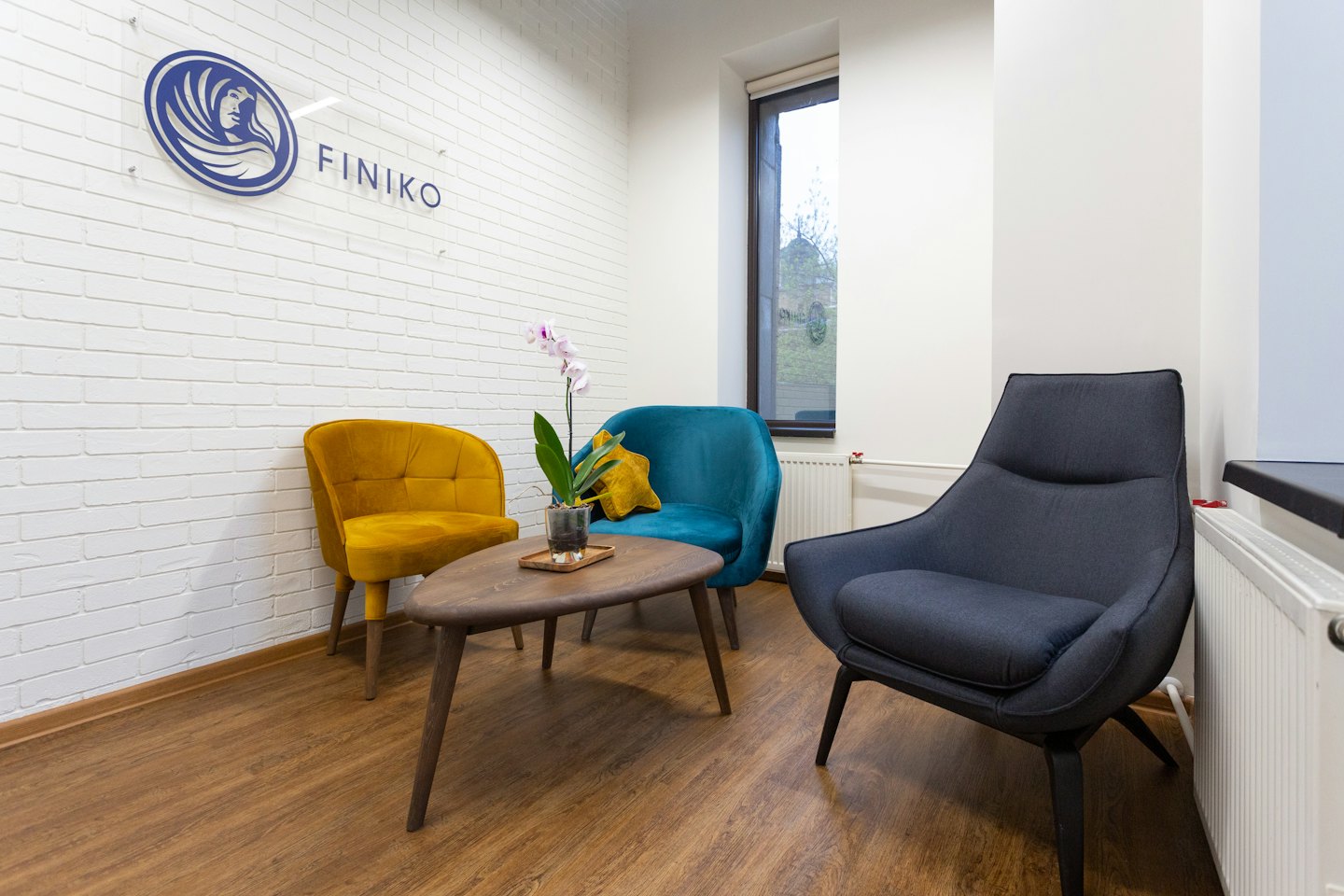 Drei bunte Sessel stehen um einen Couchtisch in einer Bürolobby.